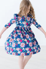 Mila Vintage Garden Ruffle Twirl Dress in teal floral print with pink blooms, 3/4 sleeves, and ruffle shoulders on a twirling girl