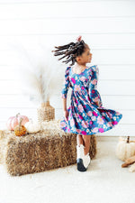 Mila Vintage Garden Ruffle Twirl Dress in teal floral print with pink blooms, shown twirling on a girl with locs, back view