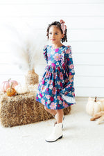 Mila Vintage Garden Ruffle Twirl Dress in teal floral print with ruffled shoulders, worn by a toddler girl in a fall lifestyle setting.