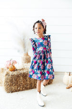 Mila Vintage Garden Ruffle Twirl Dress in teal floral print with flutter sleeves, worn by a young girl with white cowboy boots.