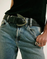 Free People Wtf Noa Belt in black leather with crescent-shaped antique brass buckle, worn over light wash distressed jeans.