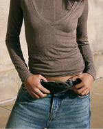 Free People Wtf Noa Belt in black, worn with low-rise jeans and a brown ribbed top, close-up showing oval buckle detail.