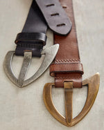 Free People Wtf Noa Belt in black leather with antiqued silver buckle alongside brown version with brass buckle, close-up flat lay