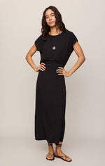 Z SUPPLY Anika Midi Dress in Black, front view on model, cap sleeves, smocked waist, maxi length with side slit, paired with strappy sandals.