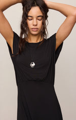 Z SUPPLY Anika Midi Dress in Black on model, featuring draped bodice, cap sleeves, empire waist, paired with silver pendant necklace.