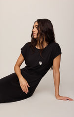 Z SUPPLY Anika Midi Dress in Black — model seated on floor in relaxed cap-sleeve dress with draped silhouette and silver pendant necklace
