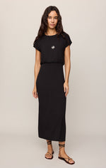 Z SUPPLY Anika Midi Dress in Black — front view on model, cap sleeves, elastic waist, maxi length, worn with lace-up sandals and pendant necklace.
