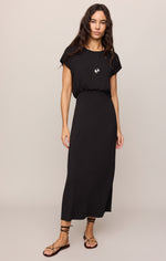 Z SUPPLY Anika Midi Dress in black, front view on model, cap sleeves, elastic waist, maxi length, worn with strappy sandals and pendant necklace.