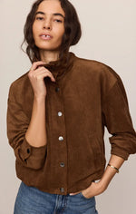 Z SUPPLY Corin Bubble Hem Jacket in saddle brown suede, snap-button front, mock neck, worn by model with jeans