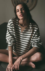 Z SUPPLY Low Key Stripe Sweatshirt in Monstera, olive and cream horizontal stripes, worn by model seated cross-legged