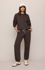Z SUPPLY Boyfriend Sweatshirt in Cocoa Bean dark brown, worn by model with matching joggers, white cap, and sneakers — front view
