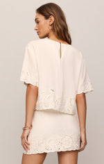 Z SUPPLY Daya Embroidered Top in White, back view on model, featuring eyelet lace trim, flutter sleeves, and scalloped hem