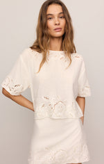 Z SUPPLY Daya Embroidered Top in white, featuring eyelet floral cutwork, short puff sleeves, and scalloped hem, worn by model