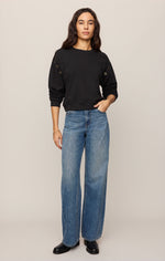 Z SUPPLY Axel Grommet Sweatshirt in black with gold grommet details on sleeves, worn by model with wide-leg jeans, front view.