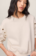 Z SUPPLY Axel Grommet Sweatshirt in Sandstone, front view on model, featuring gold grommet details along sleeves and relaxed crewneck fit.