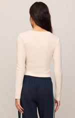 Z SUPPLY All In Henley Top in Sandstone, back view on model, cream ribbed long-sleeve crop top paired with navy track pants.