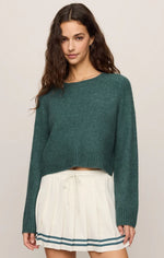 Z SUPPLY Stand In Sweater in Emerald Cove, a teal-green cropped knit pullover with crew neck, worn by a model with a white pleated mini skirt.