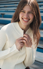 Z SUPPLY Summit Half Zip Sweater in Sandstone, cream ribbed knit pullover with silver zipper, worn by smiling model at bleachers