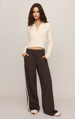 Z SUPPLY Summit Half Zip Sweater in Sandstone, cream ribbed knit crop top with gold half-zip, worn by model with wide-leg brown track pants.