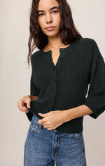 Z SUPPLY Valor Cardigan in Emerald Cove, a dark green cropped knit cardigan with button front and 3/4 sleeves, worn by a model with jeans.