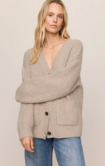 Z Supply Whitmore Cardigan in light khaki, worn by model, featuring V-neck, ribbed knit, button front, and front patch pockets