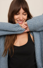 Z SUPPLY Whitmore Cardigan in Mineral Blue, worn by smiling model over black tank top, showing ribbed knit texture and sleeves