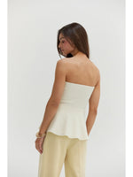 Crescent Bella Jacquard Knit Peplum Top in Cream, back view on model, strapless with flared peplum hem, paired with pale yellow trousers.