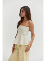 Crescent Bella Jacquard Knit Peplum Top in Cream, strapless style with flared hem, worn by model with light tan trousers, side view.