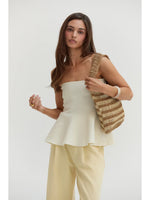 Crescent Bella Jacquard Knit Peplum Top in Cream, front view on model styled with pale yellow trousers and striped straw tote bag.