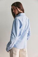 Free People Benny Slim Oxford in Blue Combo — back view on model, light blue cotton shirt with collar and button cuffs, paired with cream cargo pants.