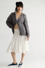 Free People Opal Cardigan in Steel Grey, chunky cable-knit with button front, worn by model over white midi skirt and blue sneakers