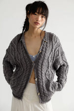 Free People Opal Cardigan in Steel Grey chunky cable-knit with button front, worn open over a striped bralette by a model