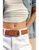 Free People WTF Jona Belt in Rustic Russet — tan leather belt with slot perforations and brass buckle, styled on model with white jeans.
