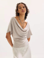 Free People Waterfall Cowl in Chateau Grey — model wearing draped cowl-neck top with flutter sleeves and layered silver chain necklaces, front view.