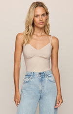 Z Supply Luxe Smooth Essential Tank in Frosted Pearl, a pale nude beige V-neck bodysuit with thin straps, worn by a model with light-wash jeans, front view.