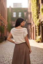 Sadie and Sage Adara Open Knit Sweater Vest in Cream, back view on model, paired with brown maxi skirt