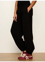 Sanctuary Micro Balloon Pant in black, shown on model with dropped crotch, tapered ankles, side pockets, paired with burgundy sneakers