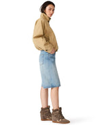 Steve Madden Fayden Jacket in tan/khaki worn by model with denim midi skirt and brown suede wedge sneakers, side view.