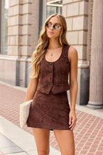 Steve Madden Fontana Vest in dark chocolate suede, buttoned front with pockets, worn with matching mini skirt by blonde model outdoors.