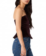 Steve Madden Dawnette Top in Deep Fig — strapless dark plum velvet corset top with peplum hem, side view on model