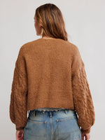 Free People Thistle Cardi in Macadamia, back view on model, warm camel bouclé knit with cable-knit balloon sleeves and cropped length.