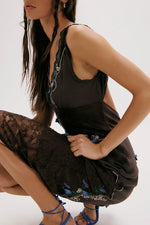 Free People Meet Again Midi dress in black with lace trim and floral embroidery, worn by model in seated pose