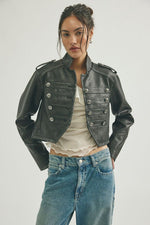 Free People Ryland Vegan Band Jacket in black, cropped military-style with silver buttons, worn over white top with blue jeans.